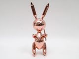 a small metal bunny figurine sitting on top of a white surface