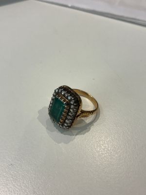 Gros plan sur une bague en or ornée d'une pierre verte