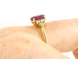 a woman ' s hand holding a ring with a ruby stone on it