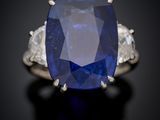 a close up of a sapphire and diamond ring on a black surface
