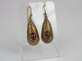 pair of gold tone earrings with garnets on clear acrylic stand