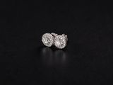 a pair of diamond stud earrings on a black background