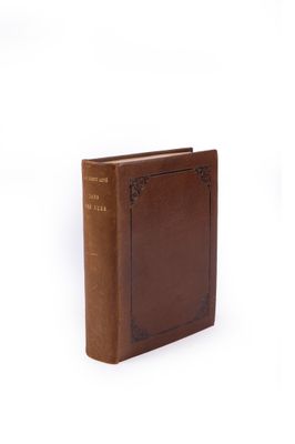 un vieux livre à la couverture brune posé sur une surface blanche