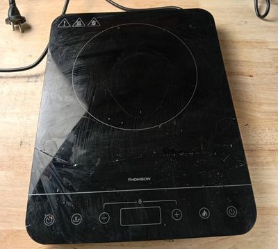 une plaque de cuisson noire surmontée d'un brûleur noir