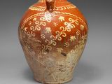 un vase marron orné de motifs sur un fond gris