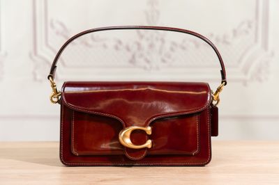 brown leather handbag with gold hardware on a wooden table