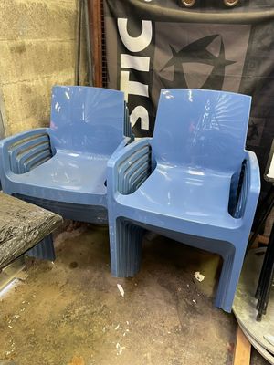 two blue plastic chairs sitting next to each other in a room