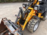 a small tractor with a front end loader attached to it ' s back end
