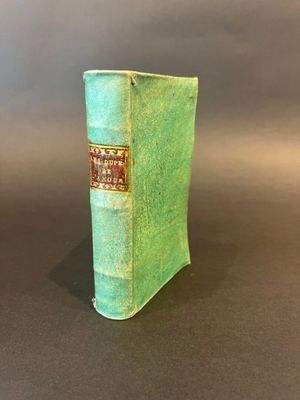 an old book sitting on top of a table covered in green cloth