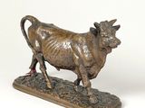 bronze statue of a bull standing on a rock on a white surface
