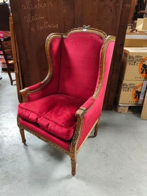 a red chair with gold trim and a wooden frame