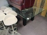 a glass table with four white stools in front of it