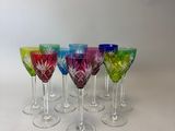 six verres à vin de couleurs différentes sont alignés sur une surface blanche