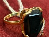 gold ring with a black stone on a red surface