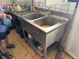 a man standing in a kitchen with a sink and a mop