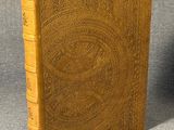 an old book sitting on top of a table next to a cup