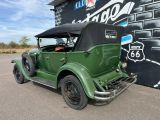 an old green car parked in front of a building
