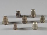 Plusieurs dés à coudre en argent sont disposés en cercle sur une surface blanche