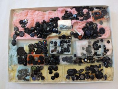 une boîte de boutons assortis posée sur une surface blanche