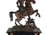 statue of a man riding a horse with a flag on top of a clock