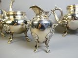 four silver teapots sitting on a table next to each other