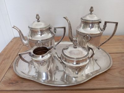 a silver tea set sitting on a tray on a table