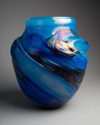 un vase bleu orné d'un motif en spirale, posé sur une surface grise