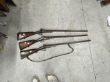 quatre armes à feu posées par terre à côté d'une paire de chaussures