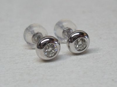 une paire de boucles d'oreilles en diamant posées sur une surface blanche