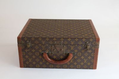 une valise marron posée sur une surface blanche