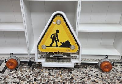 a caution sign on the floor next to a shelf