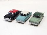four toy cars are lined up in a row on a white surface