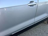 a cat that is sitting on the ground near a car