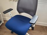 a blue office chair sitting in front of a window