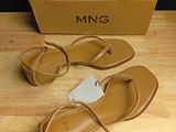 pair of women ' s tan sandals on a wooden table next to a box