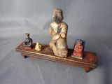 une statue représentant un homme assis sur une étagère où se trouvent d'autres objets