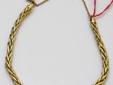a close up of a gold bracelet with a red string