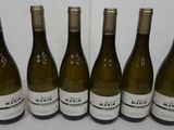 six bottles of white wine are lined up on a counter