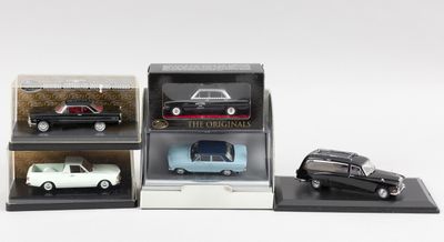 Trois modèles réduits de voitures sont exposés dans une vitrine posée sur une surface blanche.