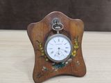 une petite horloge en bois ornée d'un motif floral