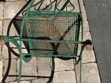 a green chair sitting on the sidewalk next to a fire hydrant