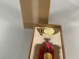 perfume bottle in a box on a white surface with a pink ribbon