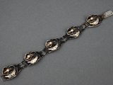 bracelet en argent orné de fleurs et de feuilles sur un fond gris