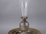 an antique silver plate with a glass vase on top of it