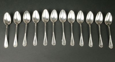 six cuillères en argent sont alignées sur une surface noire