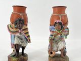 deux figurines représentant un homme et une femme portant un pot