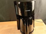 une cafetière noire posée sur une table en bois