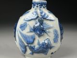 a small blue and white vase with fish on it