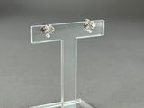 a clear acrylic display stand with two studded earrings on it