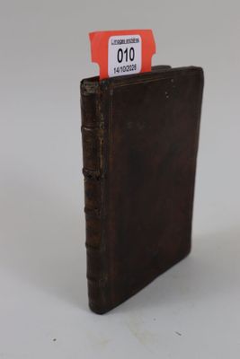un petit livre marron sur lequel est collée une étiquette rouge
